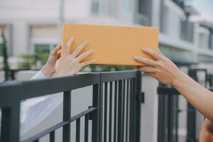 Aziatisch vrouw ontvangen Product van levering Mens Bij huis, jong eigenaar vrouw bestellen Product van smartphone sollicitatie, vrouw met online bedrijf of mkb concept. foto