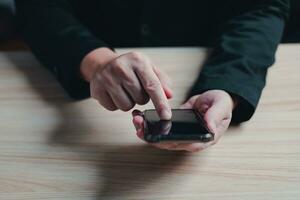 top visie van zakenman in pak zitten Aan tafel Holding en tintje smartphone. foto