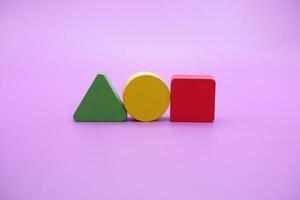 reeks van kleurrijk houten vorm speelgoed. vierkant, driehoek en ronde Aan Purper achtergrond foto