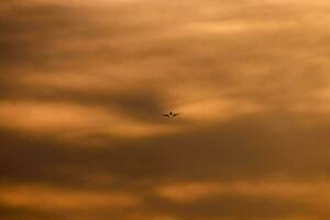 een vliegtuig vliegend in de lucht Bij zonsondergang foto