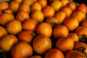 rijp oranje dadelpruimen. Aan de tafel in de markt. een bundel van biologisch kaki fruit Bij een lokaal boeren markt in dalat stad, Vietnam. kaki achtergrond. vlak leggen. foto