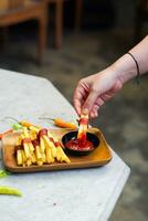 bijgesneden hand- dompelen aardappel plak naar saus dichtbij omhoog foto