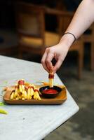 bijgesneden hand- dompelen aardappel plak naar saus dichtbij omhoog foto