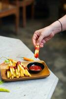 bijgesneden hand- dompelen aardappel plak naar saus dichtbij omhoog foto