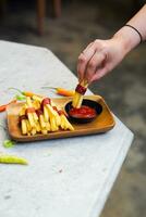 bijgesneden hand- dompelen aardappel plak naar saus dichtbij omhoog foto