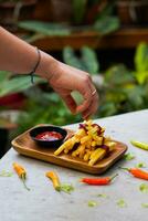 bijgesneden hand- dompelen aardappel plak naar saus dichtbij omhoog foto