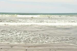 een zanderig strand met golven en rotsen foto