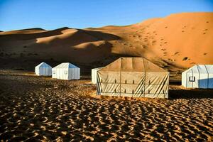 tenten in de woestijn met zand duinen in de achtergrond foto