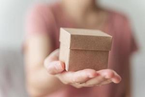 close-up van vrouw handen met een kleine geschenkdoos. kleine huidige doos in de handen van de vrouw. foto
