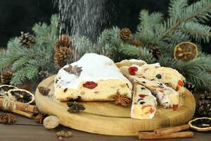 gesneden chrismas stollen met gepoederd suiker en Kerstmis decoratie foto