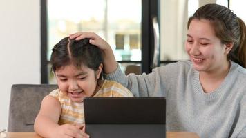 zus moedigt haar zus aan terwijl ze online studeert, een tienermeisje gebruikt haar hand op het hoofd van het meisje om te troosten.