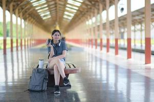 een buitenlands tienermeisje wacht op een trein op het perron om te reizen. foto