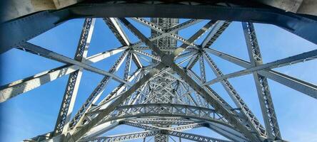 foto van een structuur van staal liggers van een brug in voorkant van een blauw lucht