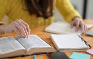 close-up shot van jonge vrouwen die gele kleding dragen, lezen boeken om zich voor te bereiden op toelatingsexamens voor de universiteit. foto