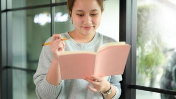 een jonge vrouw die bij het raam een boek leest. foto