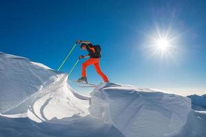 een mannelijke alpineskiër klimt op ski's en zeehondenvellen in zoveel sneeuw met obstakels foto