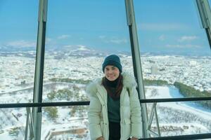 vrouw toerist bezoekende in hakodate, reiziger in trui bezienswaardigheden bekijken visie van goyokaku toren met sneeuw in winter. mijlpaal en populair voor attracties in hokkaido, japan.reizen en vakantie concept foto