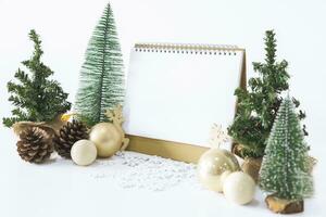de wit kalender bespotten omhoog naar invoeren tekst door de feestelijk tafereel van mooi Kerstmis boom versierd, met Kerstmis ballen, pijnboom kegels, rood huis geschenk doos gebonden gouden lintje. concept over belangrijk dag. foto