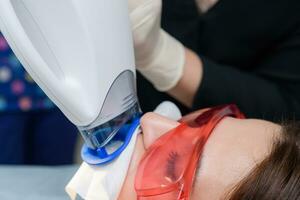 de geduldig ondergaat een procedure voor tanden bleken met een ultraviolet lamp foto