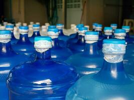 bekleed omhoog plastic groot flessen of blauw gallons van gezuiverd drinken water binnen de productie lijn. water drinken fabriek foto