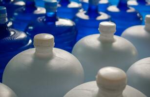 plastic groot flessen of wit en blauw gallons van gezuiverd drinken water binnen de productie lijn. water drinken fabriek foto