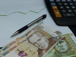 Peruaanse bankbiljetten, pen en rekenmachine op achtergrond met stijgende trend groene lijn