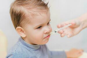 mam geeft de baby vis olie door een injectiespuit foto