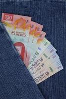 gestapelde Mexicaanse bankbiljetten van verschillende benamingen tussen blauwe denimstof