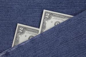 Amerikaanse bankbiljetten van twee dollar tussen blauwe denimstof foto