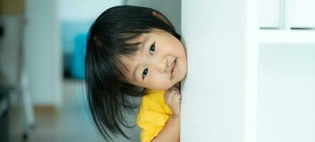 weinig Aziatisch kinderen kind spelen verbergen en zoeken staand De volgende muur huis, aanbiddelijk kind hebben pret in de huis. gelukkig familie hebben pret met kinderen, werkzaamheid, aan het leren, werkzaamheid, spel, meditatie foto