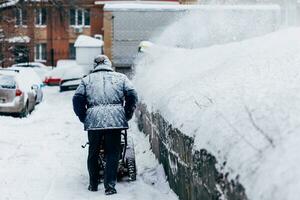 Mens reinigt de werf verwijdert sneeuw blazer foto