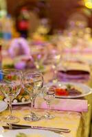 geserveerd feestelijk tafel met hapjes, bril, bril, bestek en servetten voor een banket foto