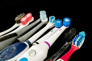 een groep van verschillend tandenborstels Aan een zwart oppervlakte foto