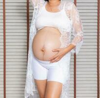 portret van een zwanger vrouw aanraken haar groot buik dichtbij omhoog, moeder, zwangerschap, mensen en verwachting. vrouw Holding groot zwanger maag foto