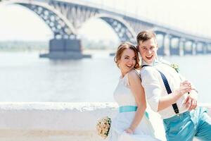 de bruid en bruidegom zijn gefotografeerd Aan de achtergrond van de brug foto
