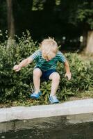 weinig jongen jumping in een plas in zomer foto