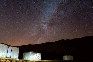 de sterren schijnen helder bovenstaand tenten in de woestijn foto