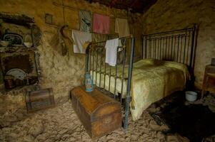 een kamer met een houten bed en kleren hangende Aan de muur foto