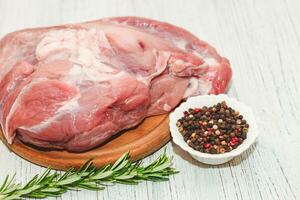 vers stuk van vlees groot varkensvlees ham Aan een bord met peper en rozemarijn. foto