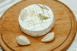 ronde kaas in Camembert gietvorm met een takje van rozemarijn, met knoflook Aan de tafel foto