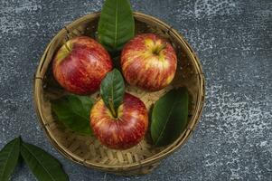 drie appels in een mand met bladeren foto