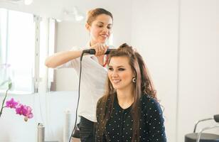 stilist drogen haar- van een vrouw cliënt Bij de schoonheid salon foto