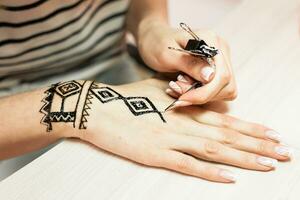 werkwijze van toepassen mehndi Aan vrouw hand- dichtbij omhoog foto