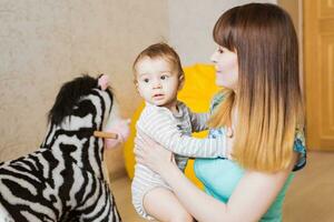 gelukkig moeder met aanbiddelijk baby jongen in de slaapkamer. foto