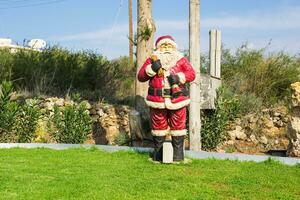 de kerstman claus pop. de kerstman standbeeld met Kerstmis decoratie Aan groen gras. foto