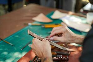 detailopname en Bijsnijden handen van leer vakman naaien een leer bruin zak voor een klant. foto