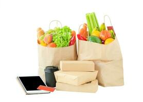 boodschappen doen Tassen met voedsel, tablet en credit kaart. online boodschappen doen concept. foto