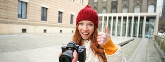 mooi leeskop meisje, fotograaf met professioneel camera duurt afbeeldingen buitenshuis, wandelen in de omgeving van stad en nemen foto's, bezienswaardigheden bekijken foto