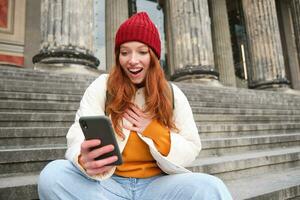 roodharige vrouw toerist praat Aan mobiel telefoon, video chatten met vrienden, zegt Hoi en golven hand- Bij smartphone camera foto