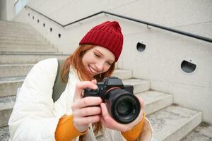 portret van vrouw fotograaf wandelen in de omgeving van stad met professioneel camera, nemen afbeeldingen vastleggen stedelijk schoten, fotograferen buitenshuis foto